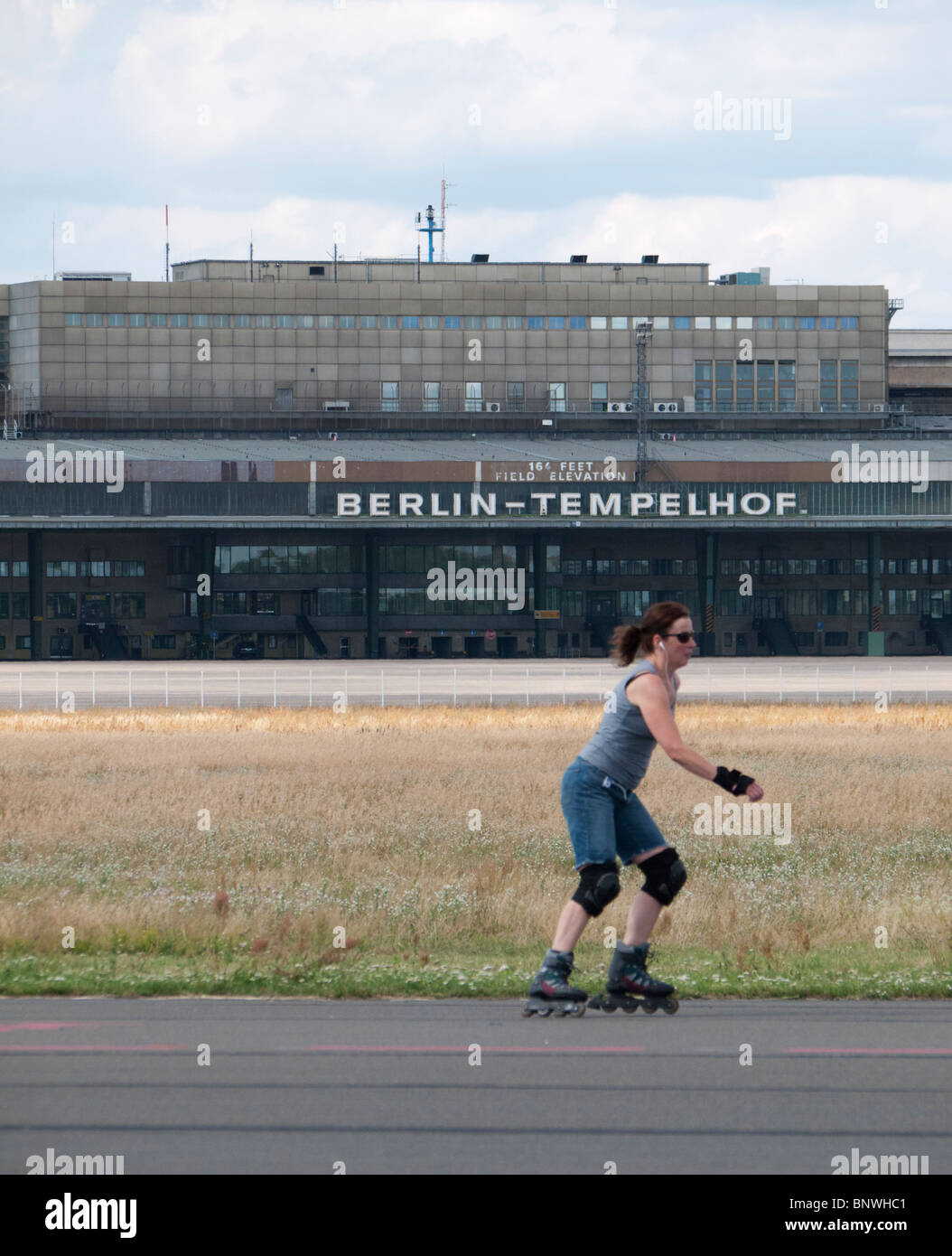 Donna inline skating lungo la pista di nuova città pubblico Tempelhofer Park sul sito del famoso ex aeroporto Tempelhof di Berlino Germa Foto Stock