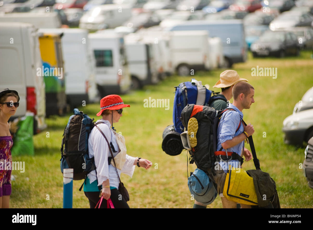 Le persone che lasciano il festival di Glastonbury alla fine del festival con le macchine parcheggiate e furgoni in background. Foto Stock