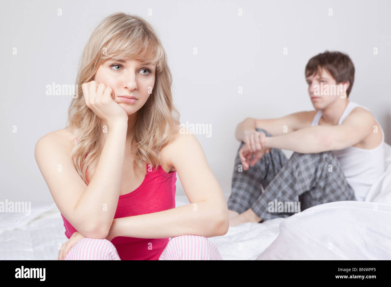 Giovane seduto sul letto dopo aver litigato Foto Stock