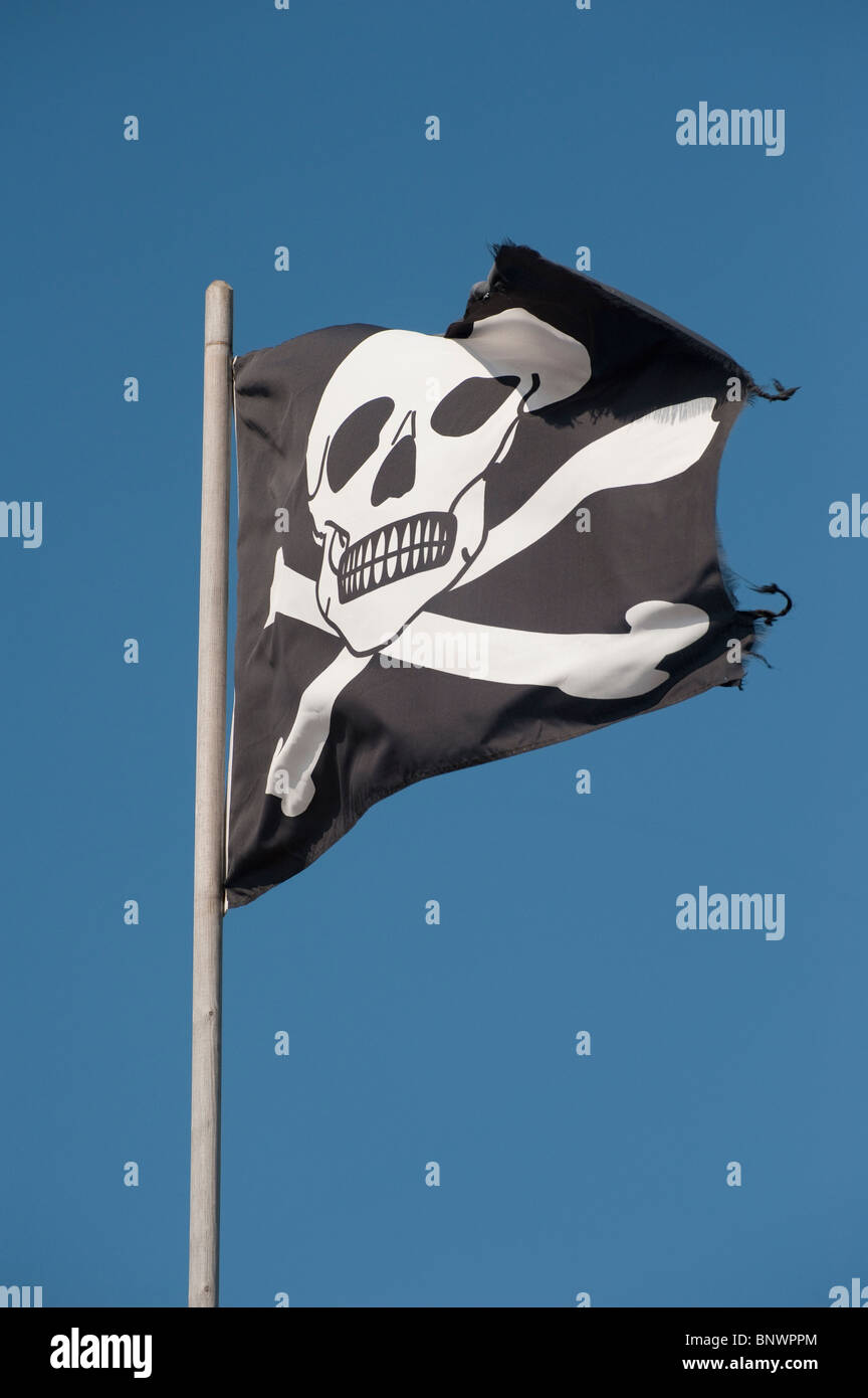 Cranio e crossbones su una bandiera in un luminoso cielo blu. Foto Stock