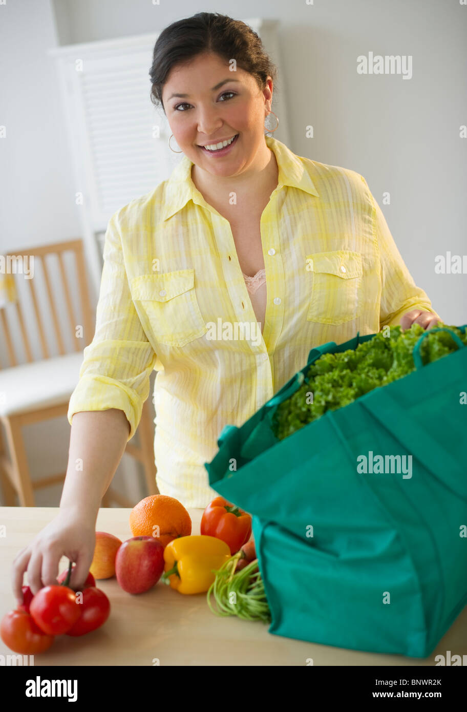Donna disimballaggio verdure dal sacchetto di negozi di generi alimentari Foto Stock