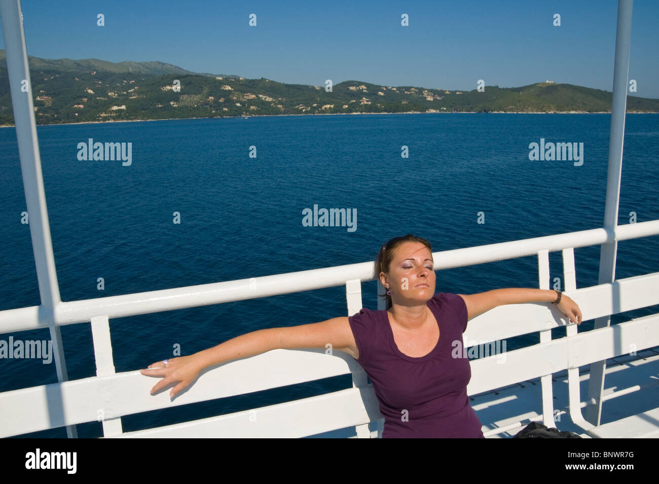 Giovane donna tourist ensoleillement se stessa sul traghetto off l'isola greca di Corfu Grecia GR Foto Stock