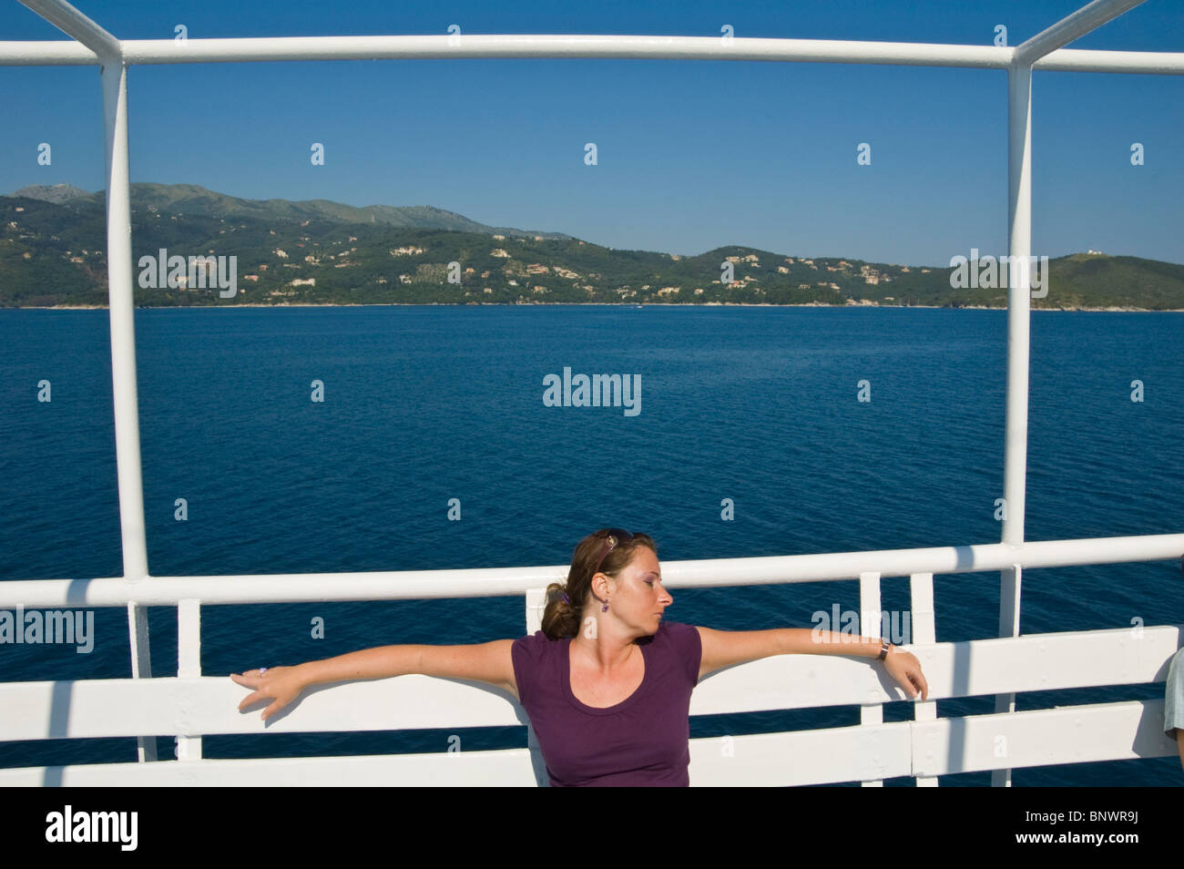 Giovane donna tourist ensoleillement se stessa sul traghetto off l'isola greca di Corfu Grecia GR Foto Stock