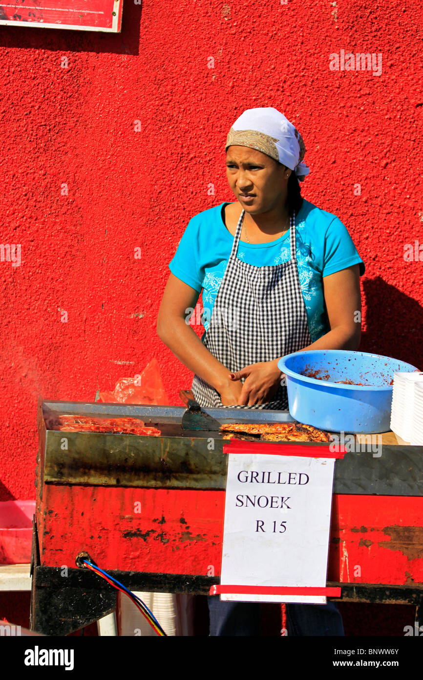 Donna locale la cottura alla griglia appena catturati snoek a Hout Bay Harbor. Foto Stock