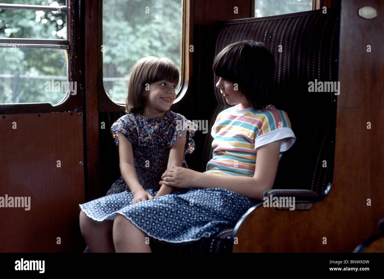 Due giovani ragazze in un vecchio treno dei pendolari a ridere e parlare insieme Foto Stock