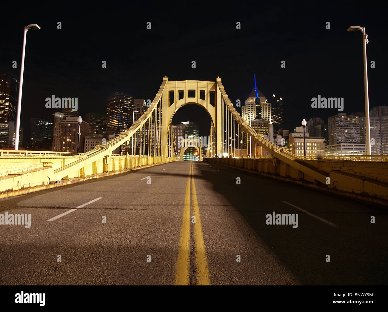 Giallo ponte che conduce al centro di Pittsburgh. Accesa con il bagliore del baseball stadium luci. Foto Stock