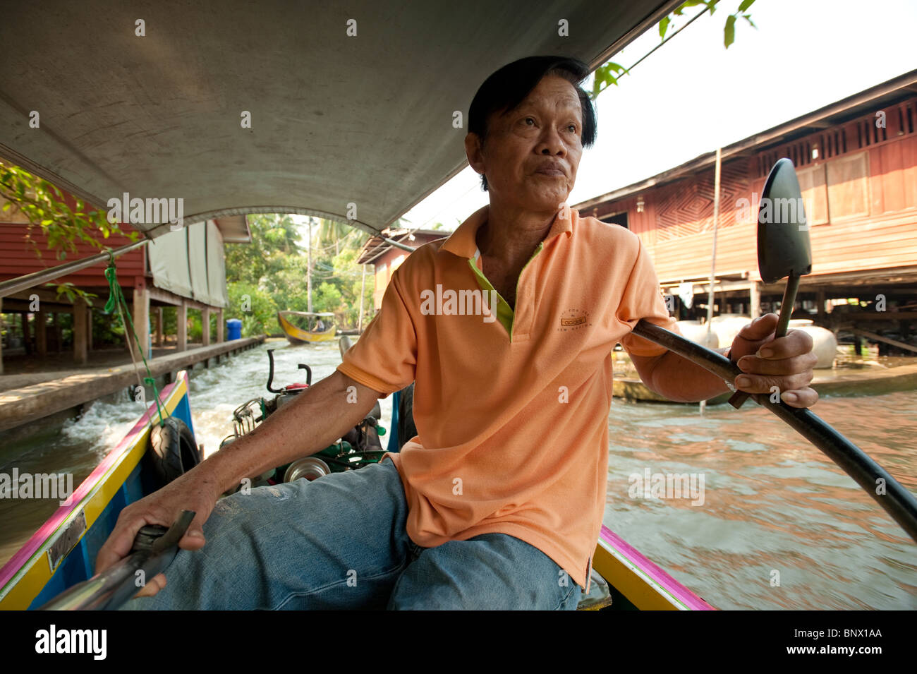 Thai uomo alla guida di una tradizionale barca long-tail al Mercato Galleggiante di Damnoen Saduak, Bangkok, Thailandia, Asia Foto Stock