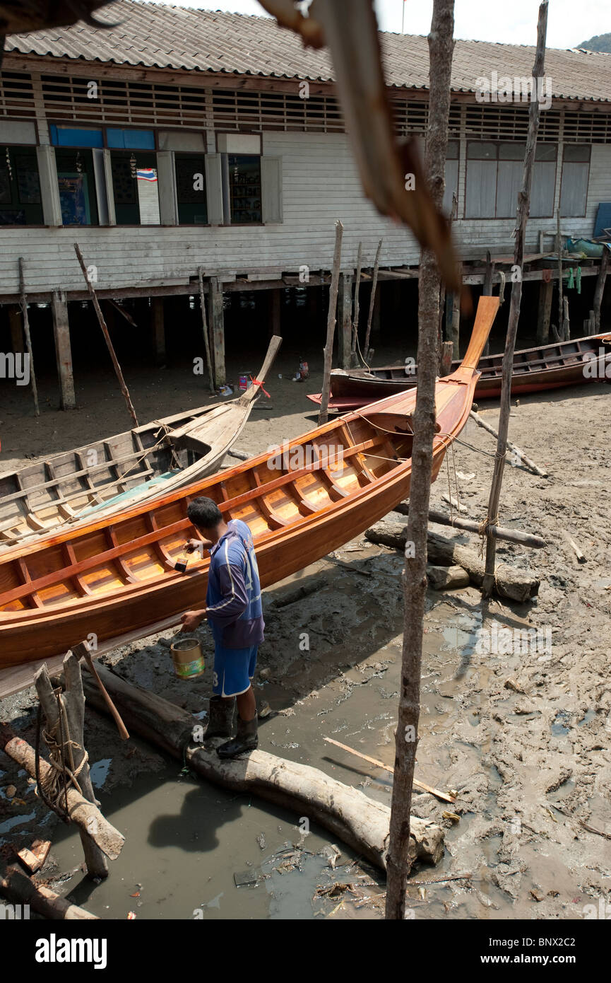 L'uomo pittura una lunga barca al mare villaggio zingaro a Koh Panyee, Phang Nga Bay, Thailandia, Asia Foto Stock