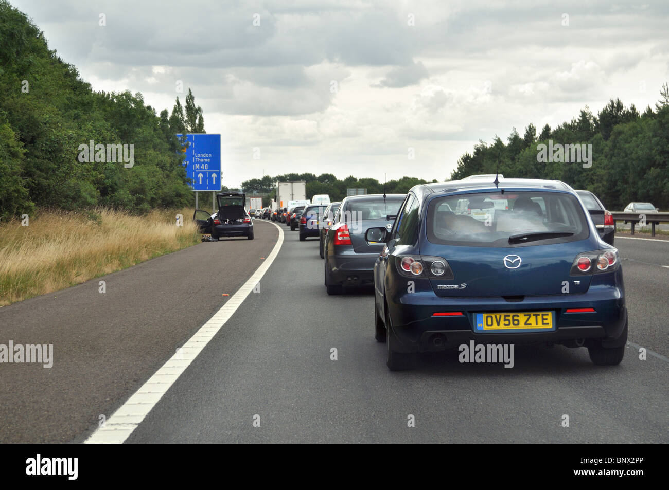 Auto parcheggiate sul disco spalla in lento movimento verso sud il traffico sulla autostrada M40 in Oxfordshire, Regno Unito. Foto Stock