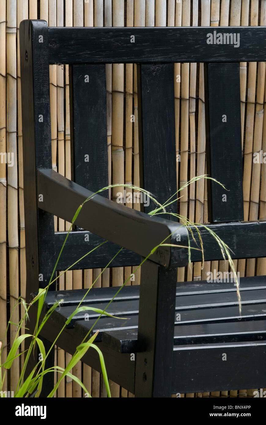 Giardino sede contro una schermata di bambù Foto Stock