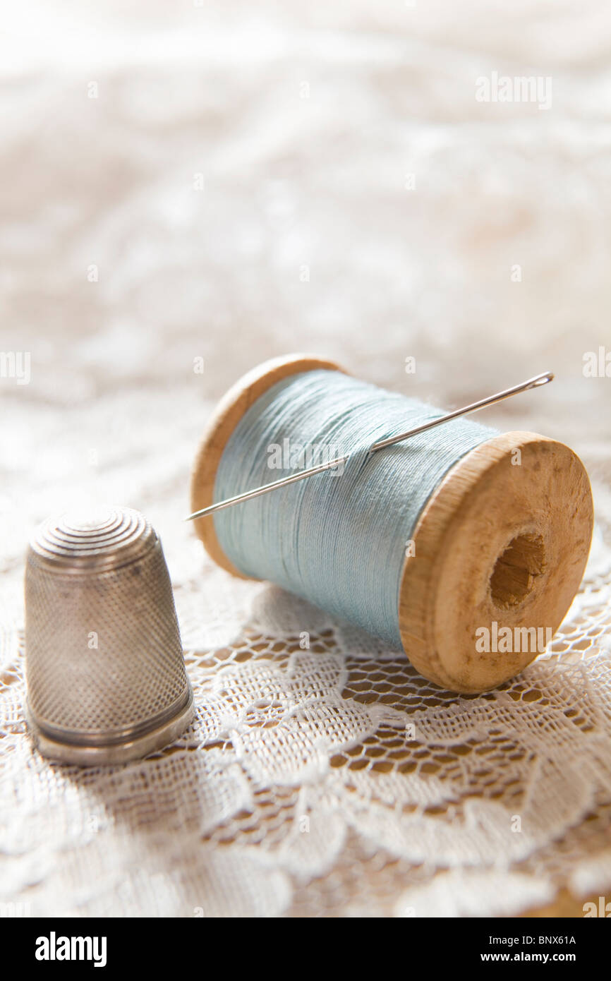 Vintage Bobina di cotone con ago e ditale in argento sul Pizzo Bianco Foto Stock