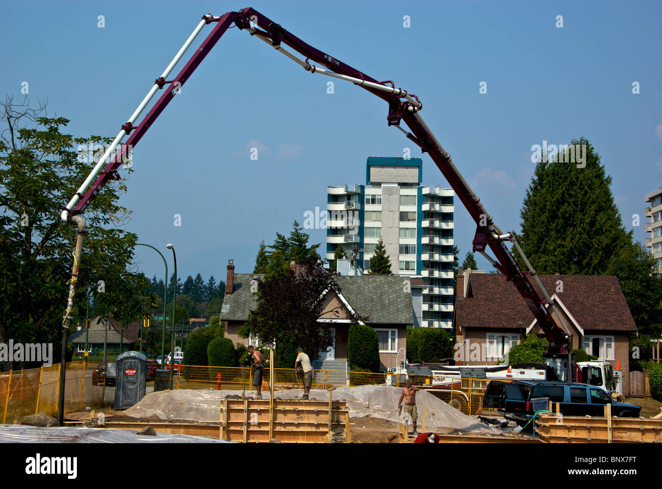 Calcestruzzo pumper carrello utilizza extra lungo il braccio idraulico tubo flessibile per raggiungere forme di fondazione a casa sito in costruzione Foto Stock