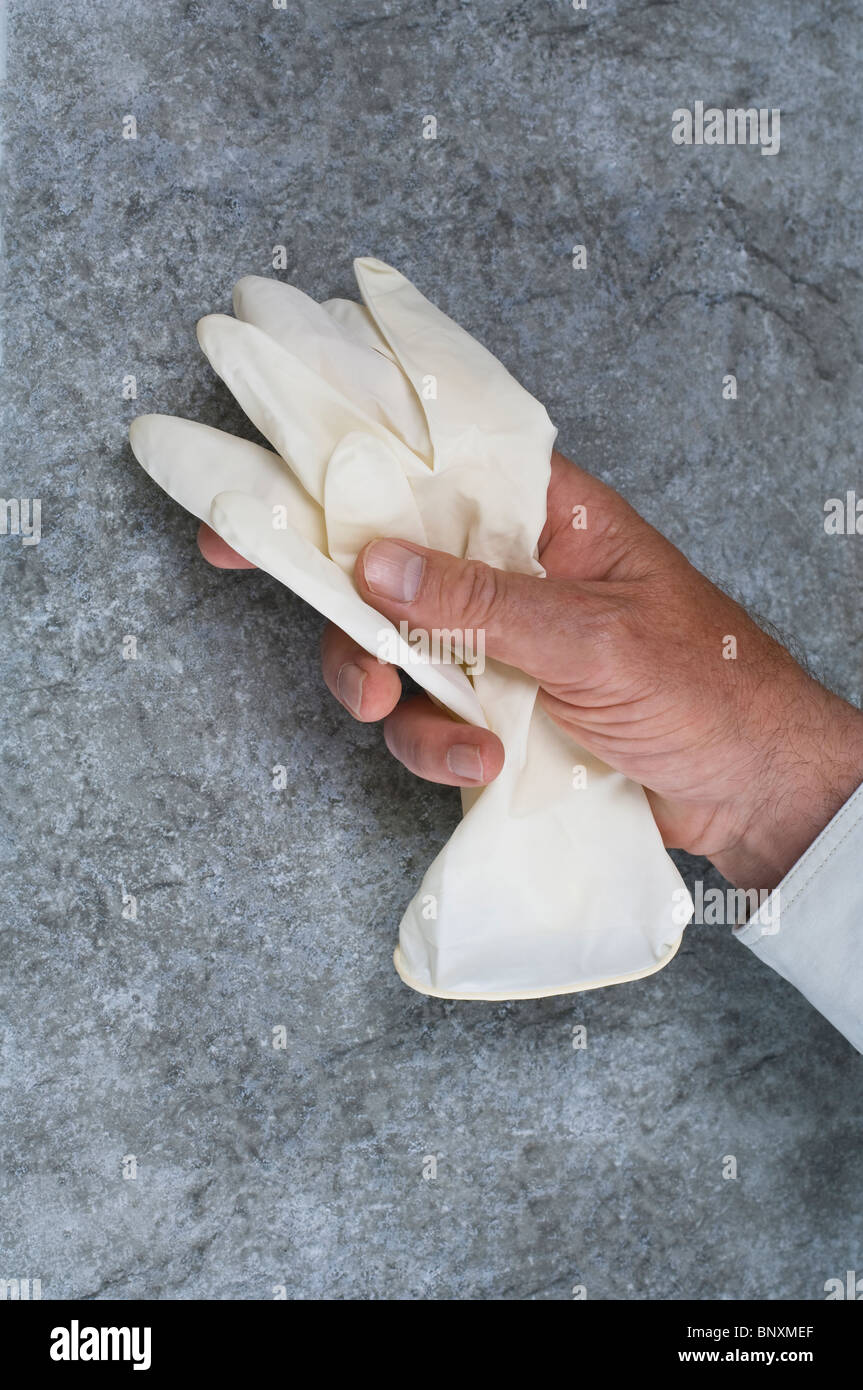 Un maschio di mano il prelievo di una coppia di medico di lattice Guanti di gomma Foto Stock