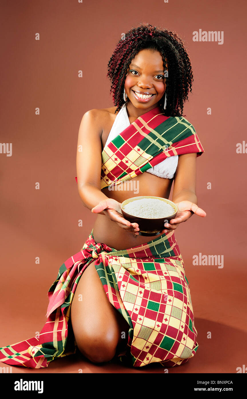 Bella giovane donna africana indossando il tradizionale stile abiti tribali in possesso di una ciotola di riso Foto Stock