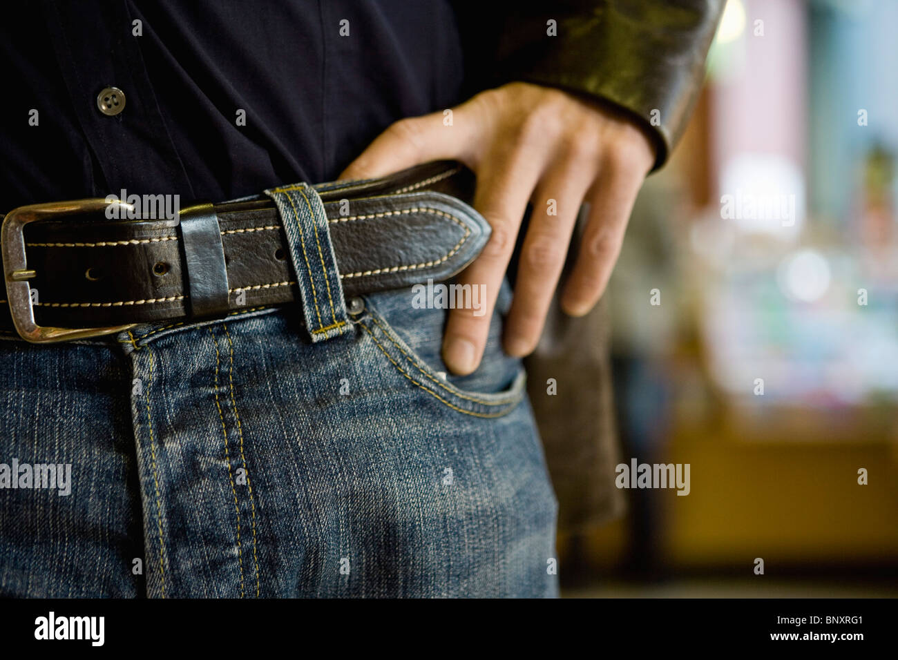 Persona che indossa jeans con cintura, mano su hip, ritagliato Foto Stock