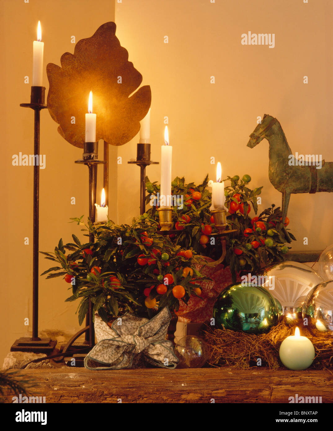 Close-up di festosa candele accese in alti candelabri accanto a bacca e  houseplants vetro metallico baubles di Natale Foto stock - Alamy