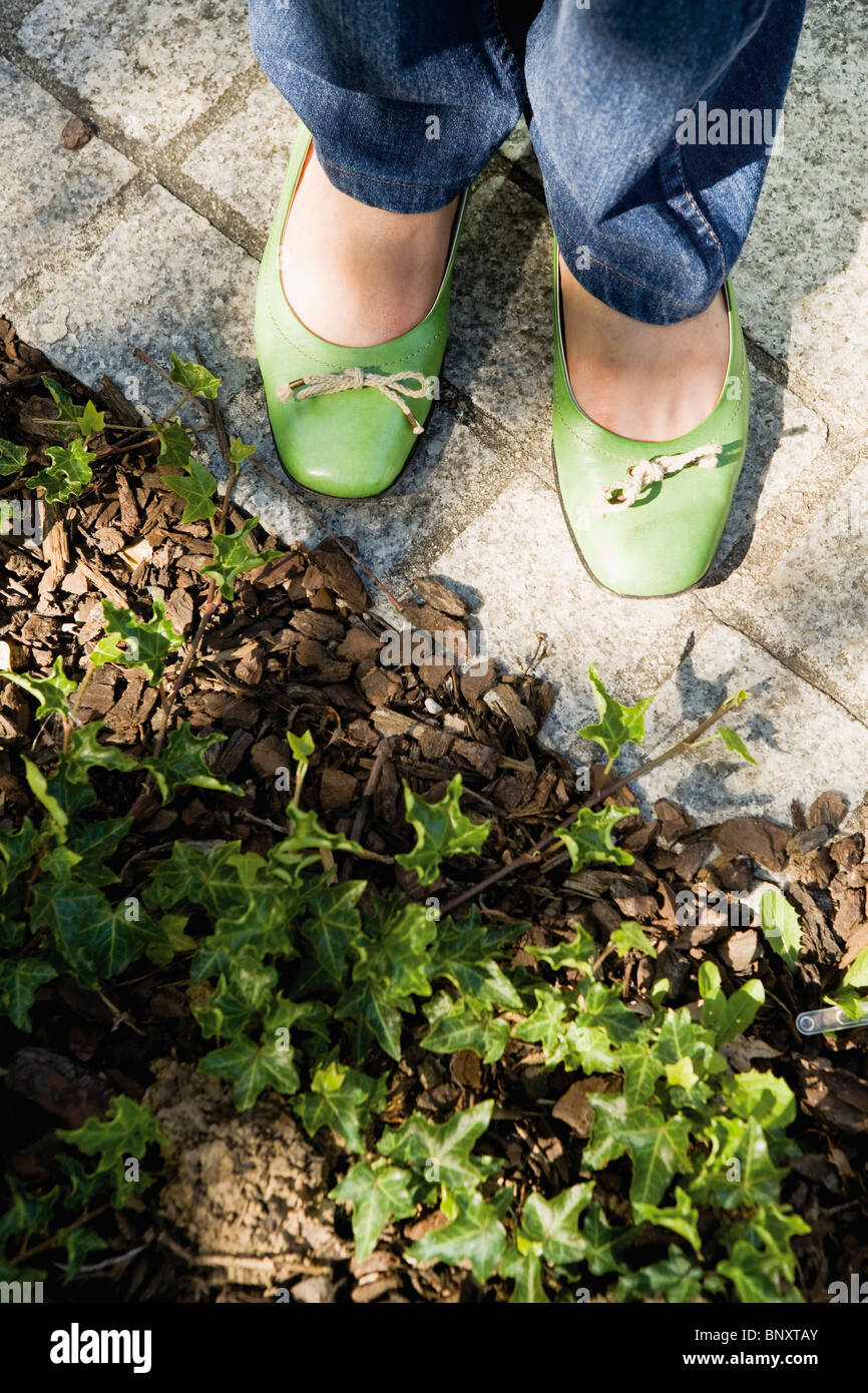 Donna in piedi sul marciapiede in corrispondenza del bordo del giardino Foto Stock
