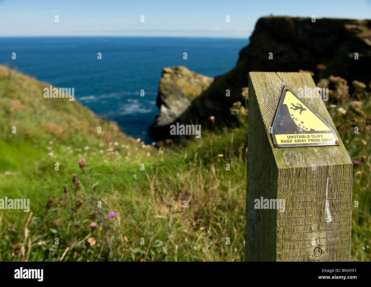 Un palo di legno con un cartello di avvertimento sulla rupe a Hells bocca in Cornovaglia. Foto di Gordon Scammell Foto Stock