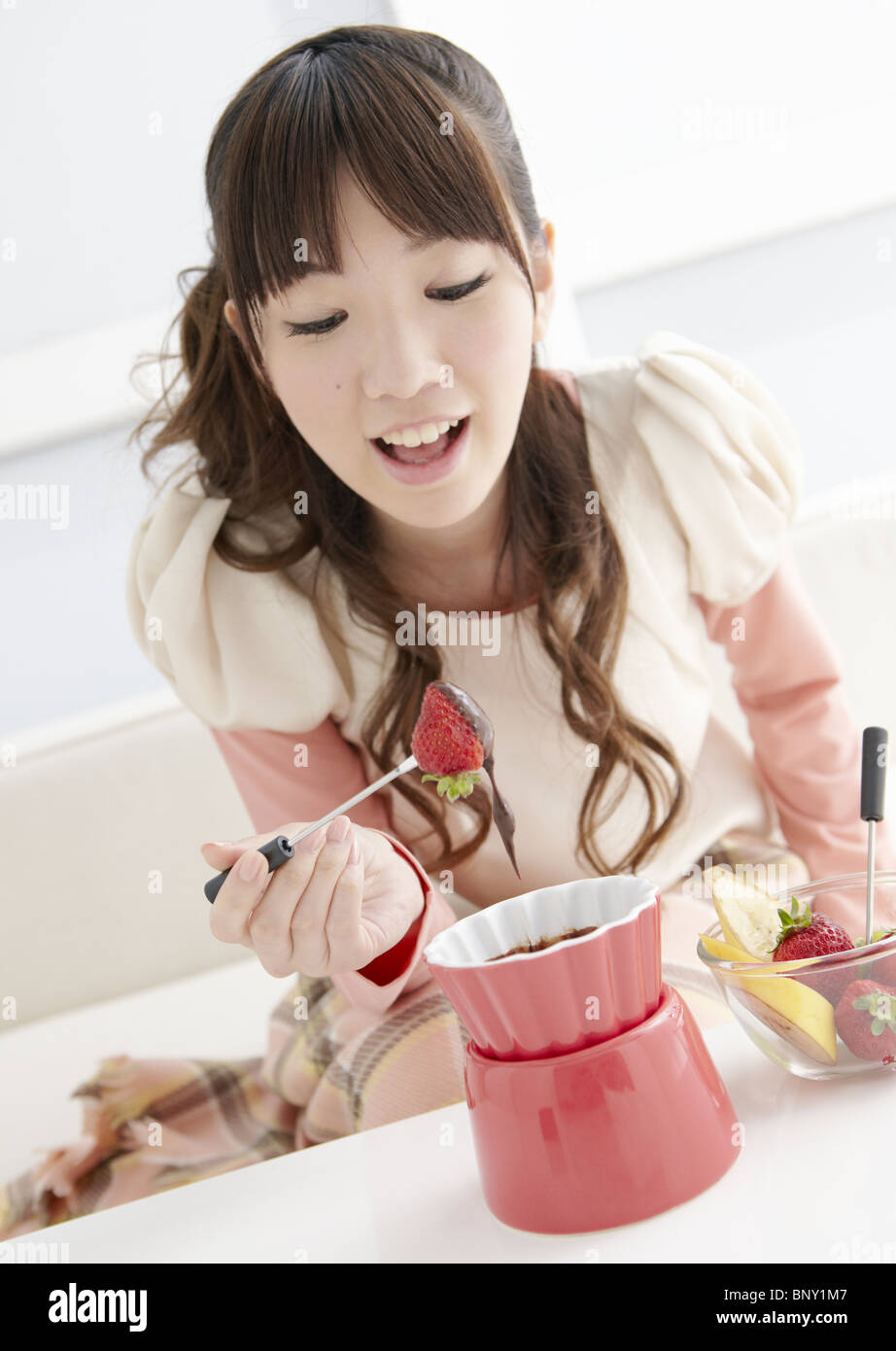 Giovane donna di mangiare la fonduta di cioccolato Foto Stock