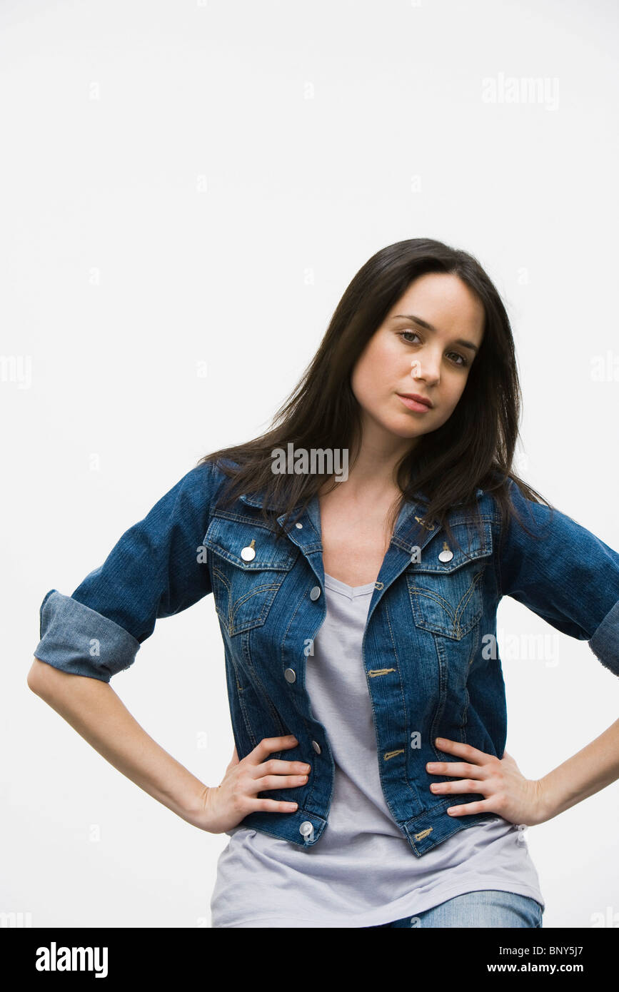 Donna indossando jean jacket, mani sui fianchi, ritratto Foto Stock