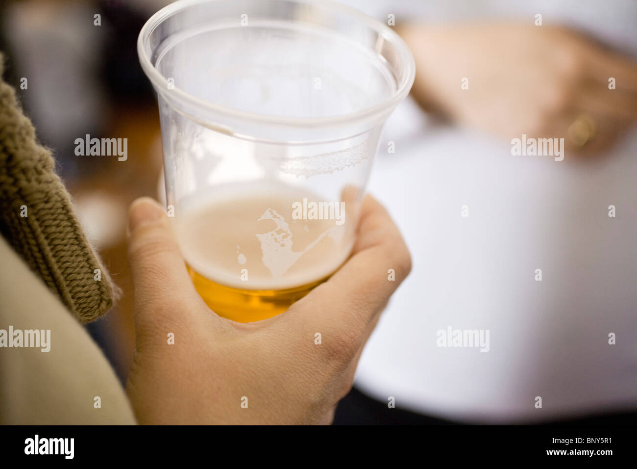 Persona in possesso di birra in una tazza di plastica Foto Stock