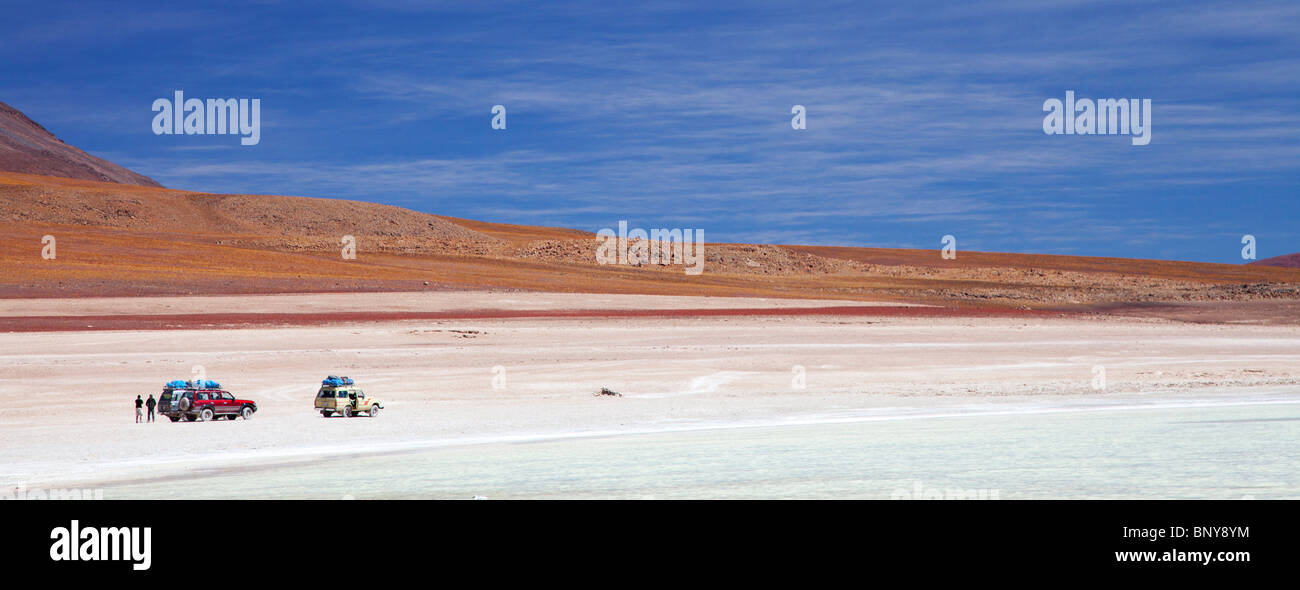 Immagine panoramica di 2 veicoli 4WD fermarsi presso un lago nel sud del deserto boliviano Foto Stock