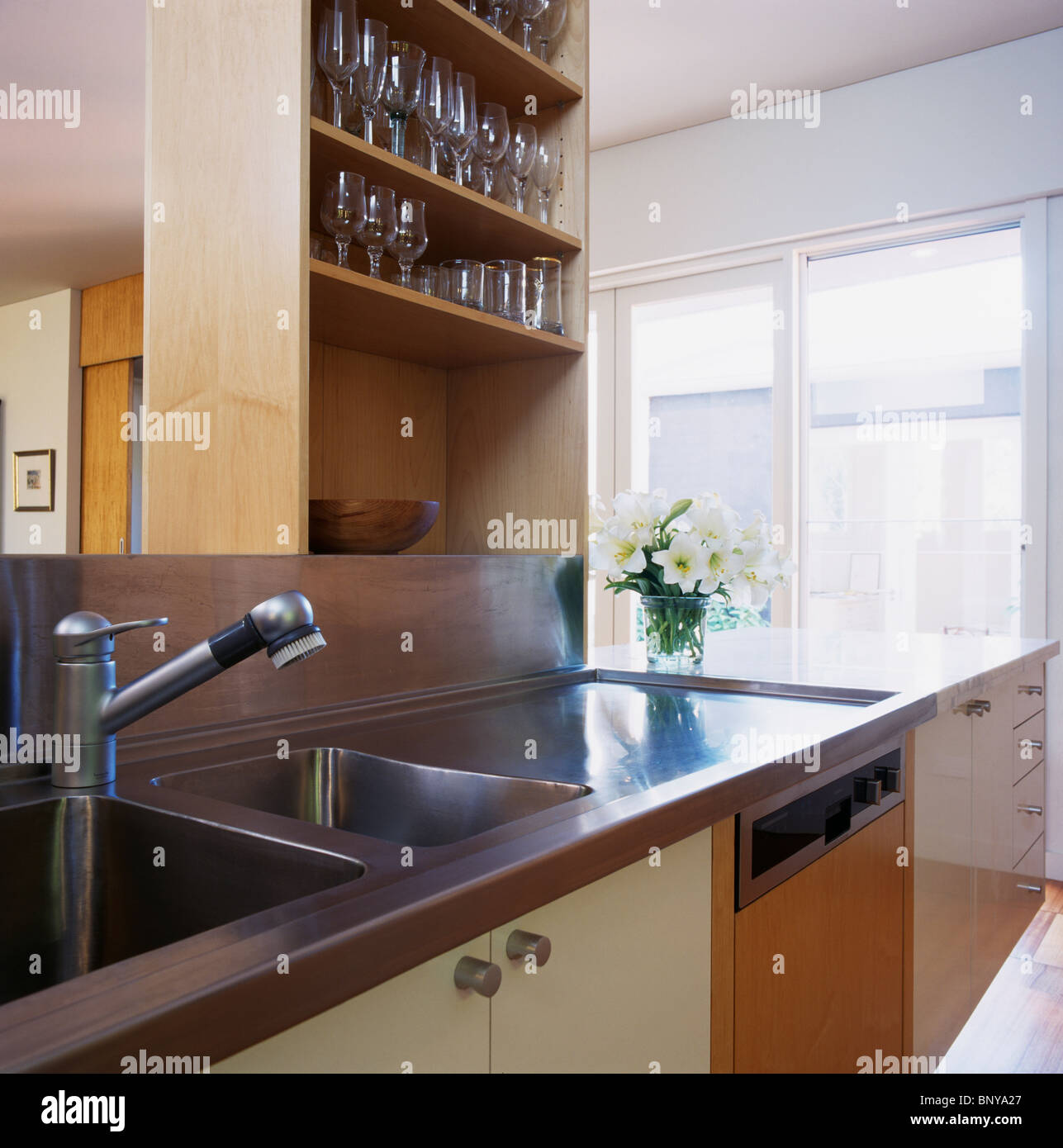 Vino-occhiali su scaffalatura sovrastante lavello in acciaio inox e piano di lavoro in cucina moderna Foto Stock