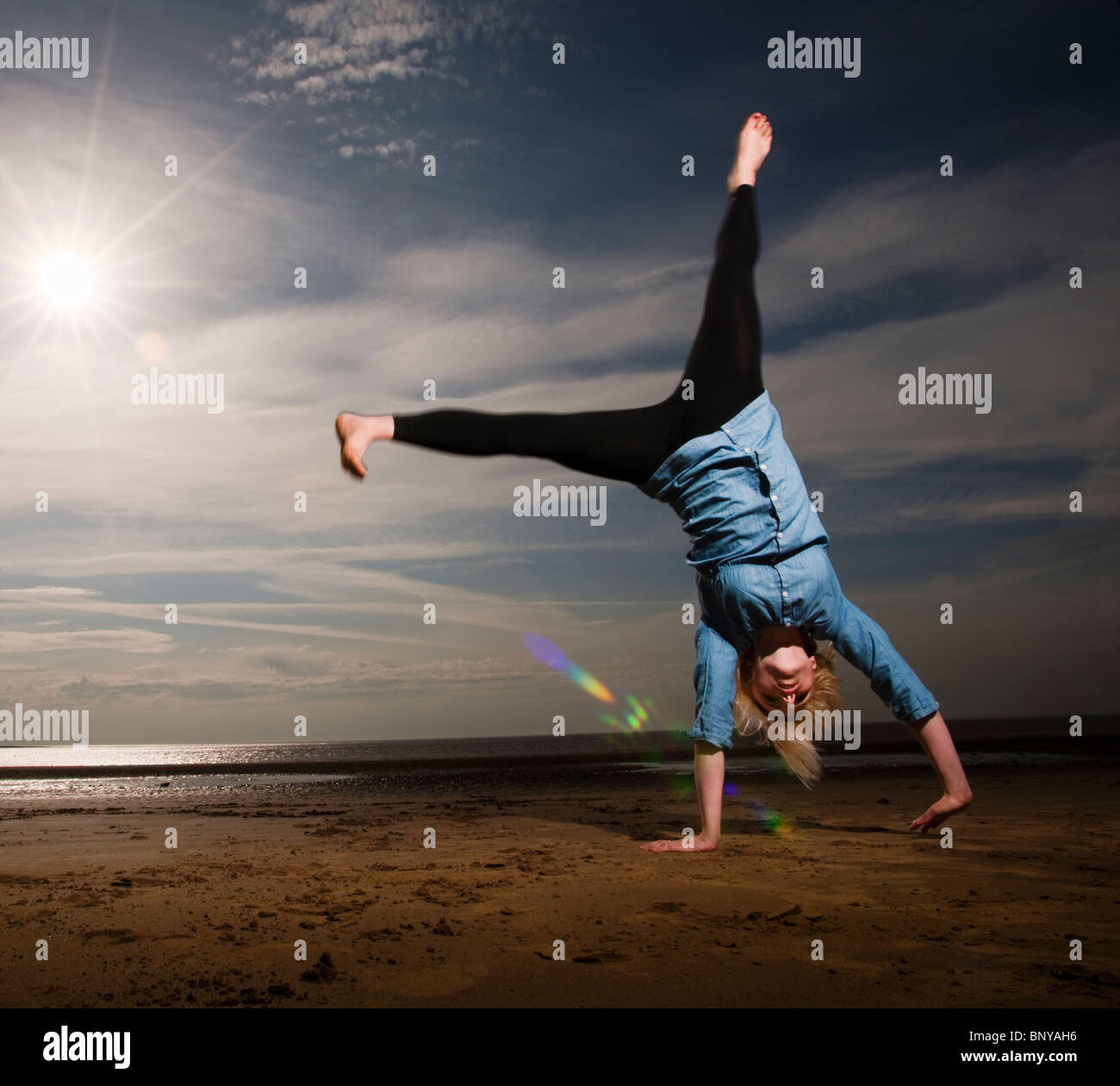 Donna cartwheeling sulla spiaggia Foto Stock