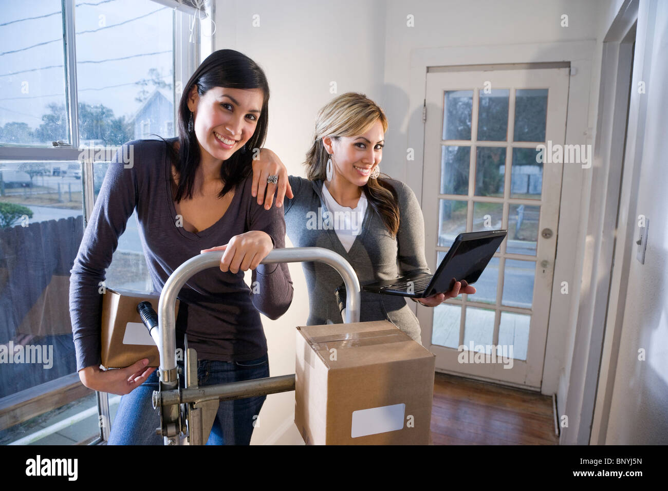 Due giovani donne che si muovono le scatole di cartone sul carrello Foto Stock