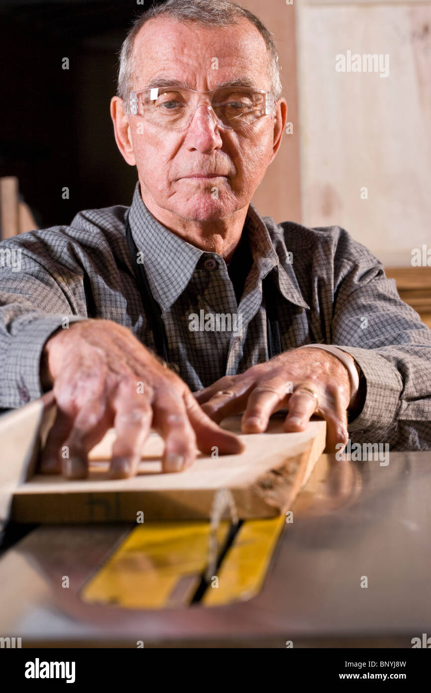 Senior uomo in macchine per la lavorazione del legno negozio utilizzando sega da tavolo Foto Stock