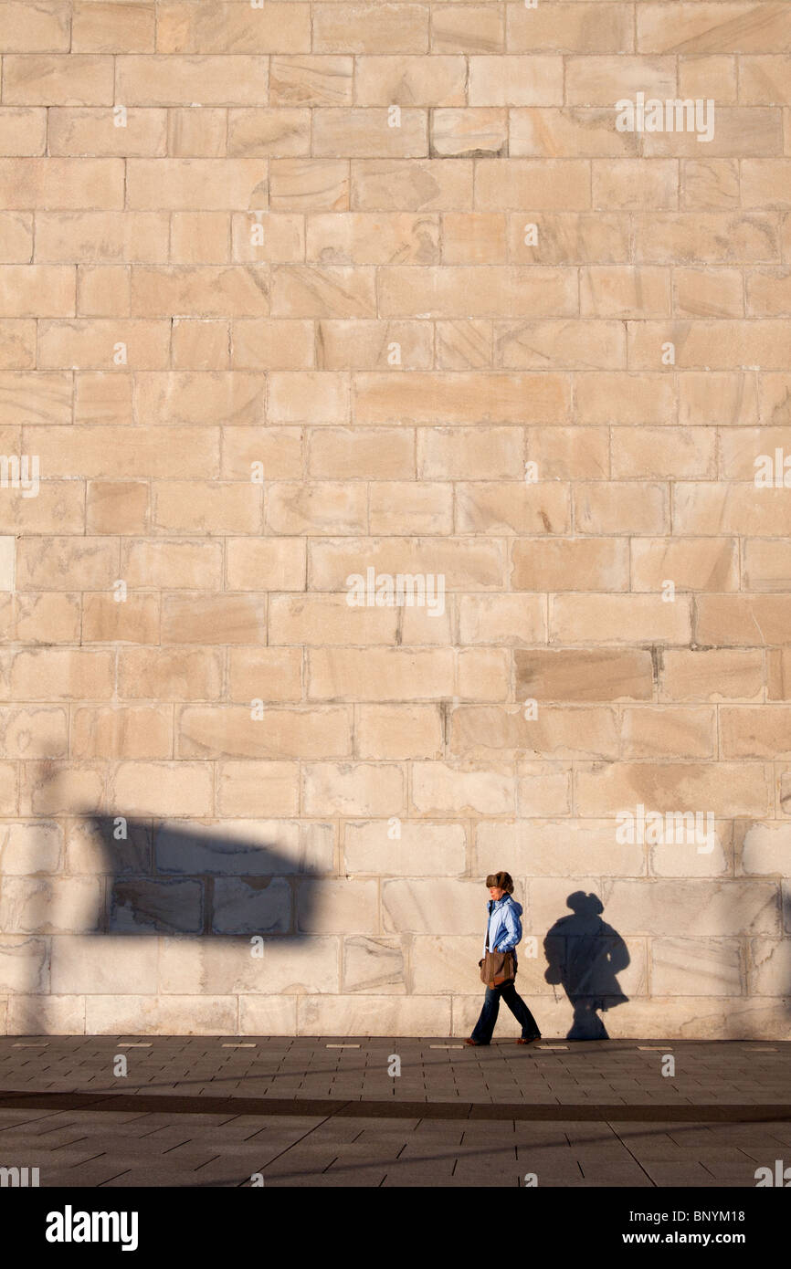 Una femmina di camminare al fianco del monumento di Washington con un ombra di una bandiera mostrato sulla parete il Monumento a Washington DC, Stati Uniti d'America Foto Stock