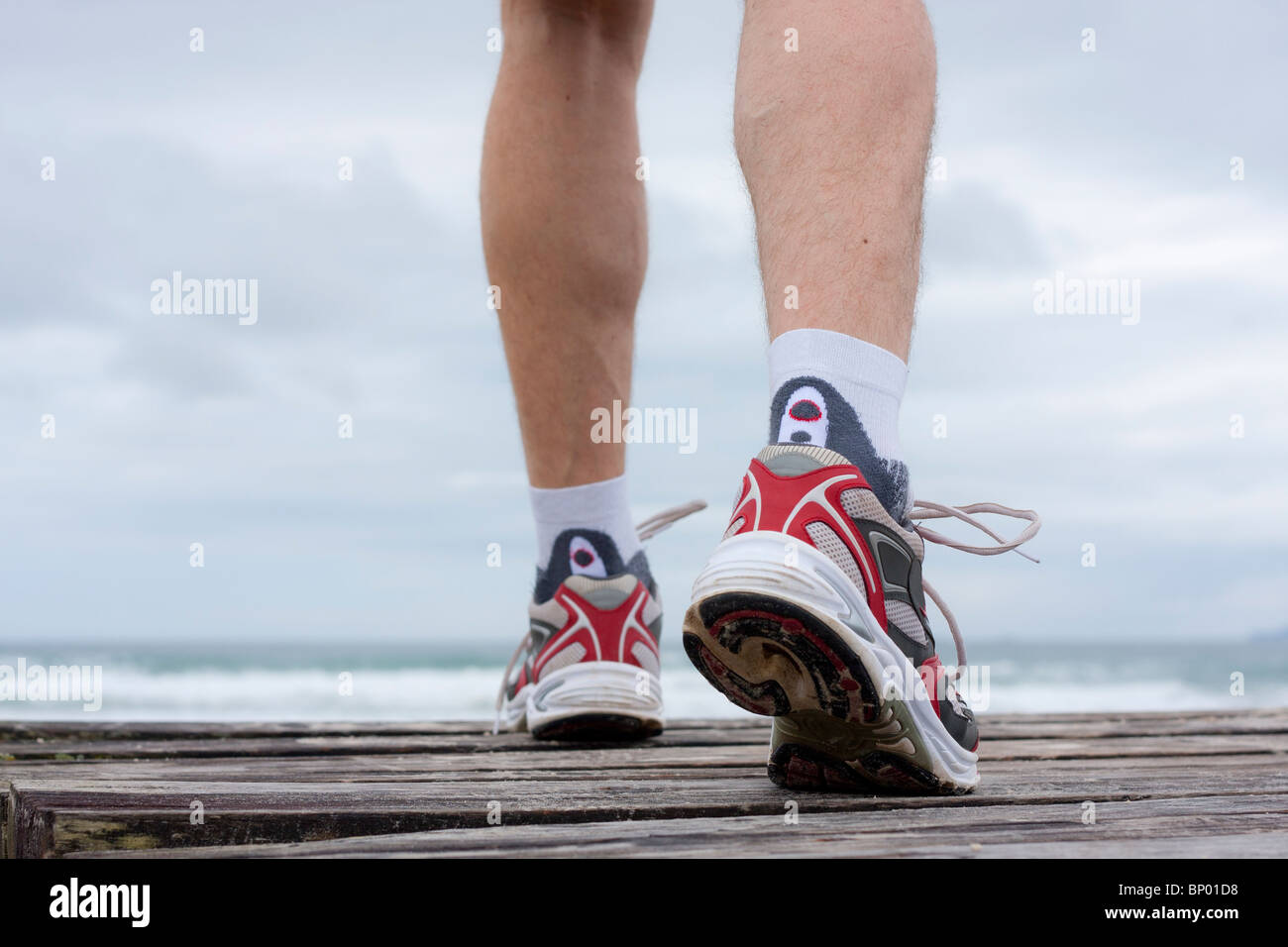 Dettagli di piedi di runner di fronte alla spiaggia Foto Stock