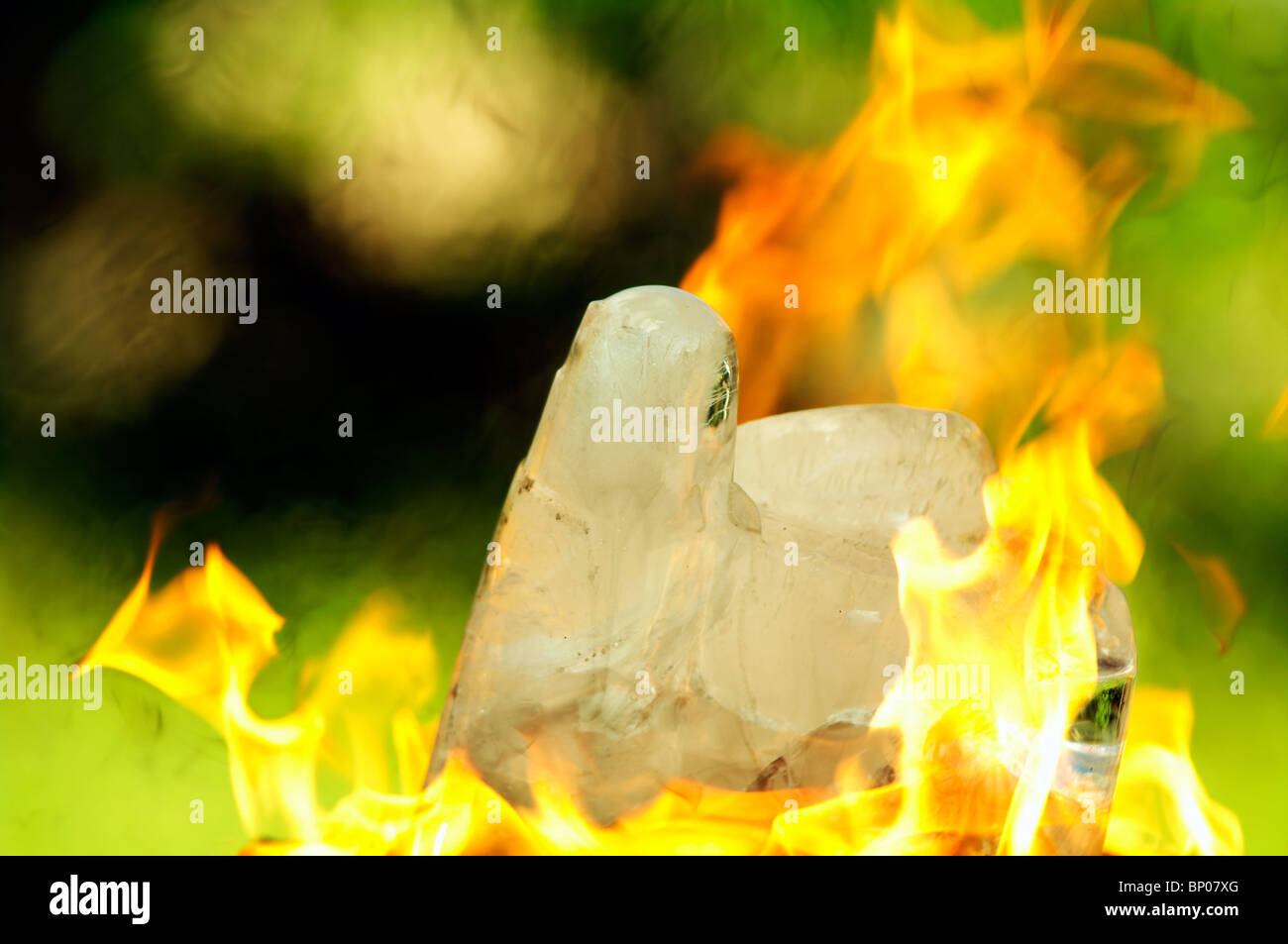 Blocco di ghiaccio che si scioglie a causa della rapida azione del fuoco. Lavoro concettuale sugli incendi nelle foreste. Un cubetto di ghiaccio che scioglie circondato da fiamme arancioni brillanti. Foto Stock