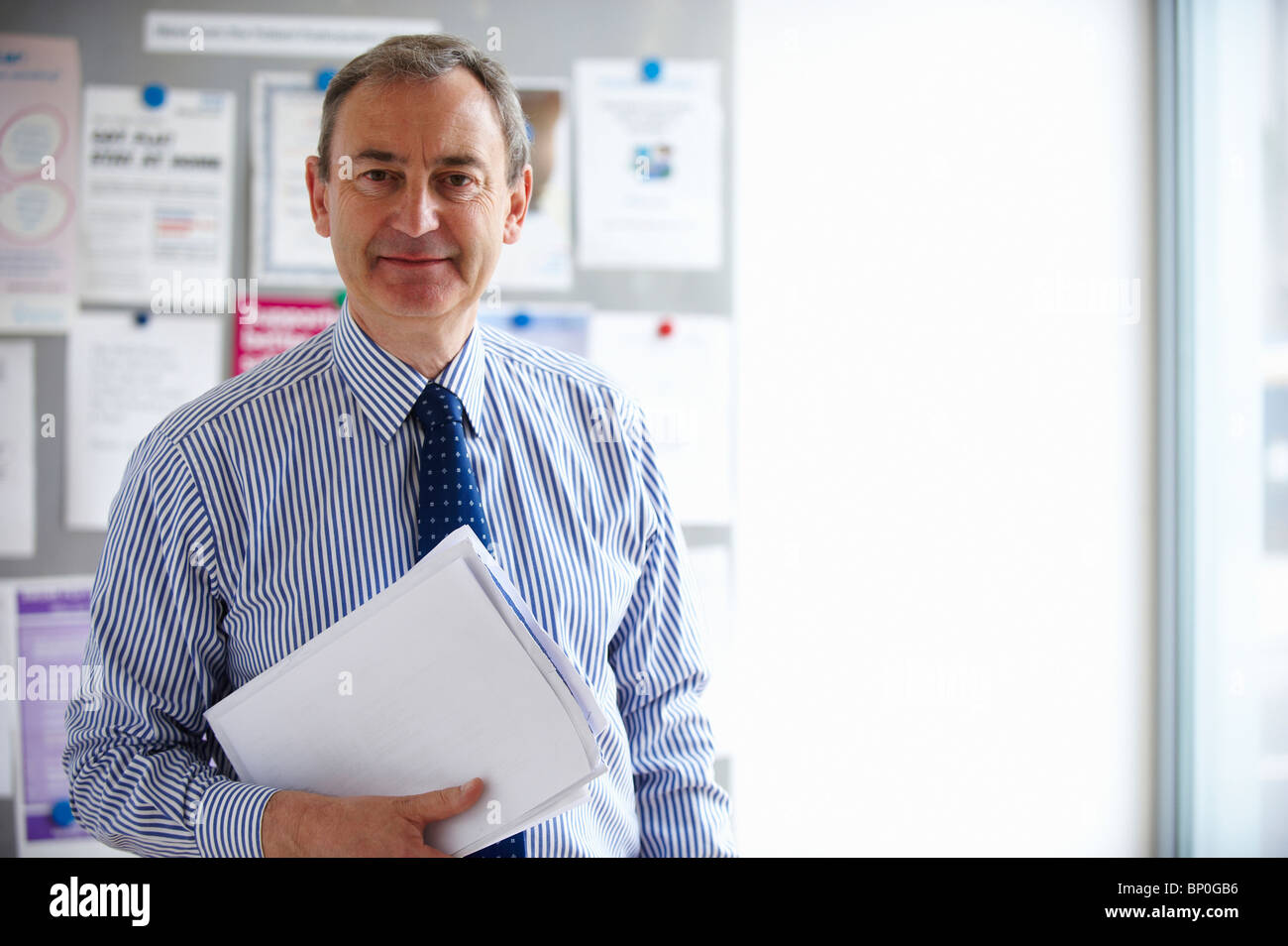 Maschio consulente medico tenendo papers Foto Stock