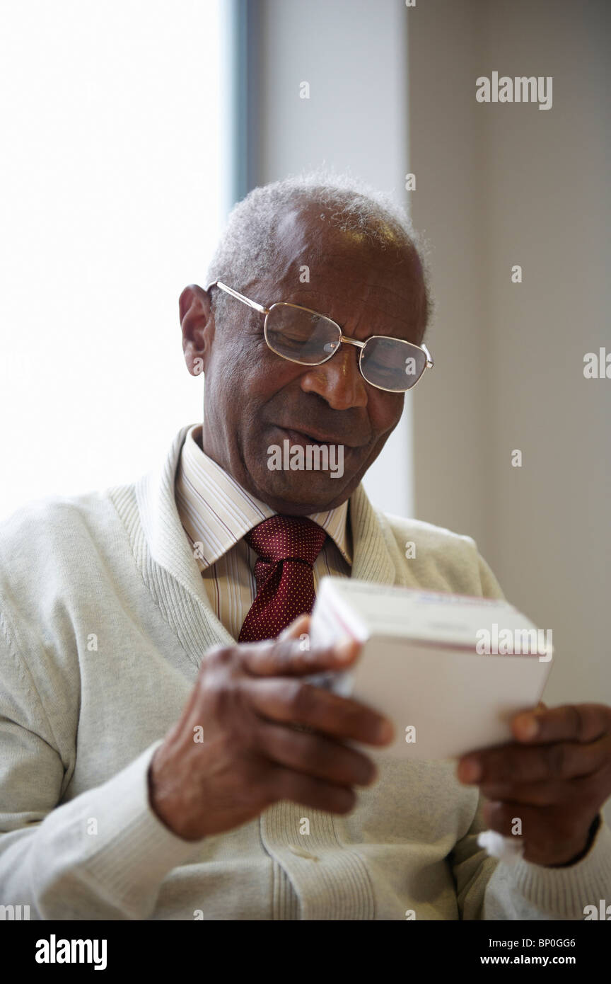 Anziani uomo nero lettura casella di medicina Foto Stock