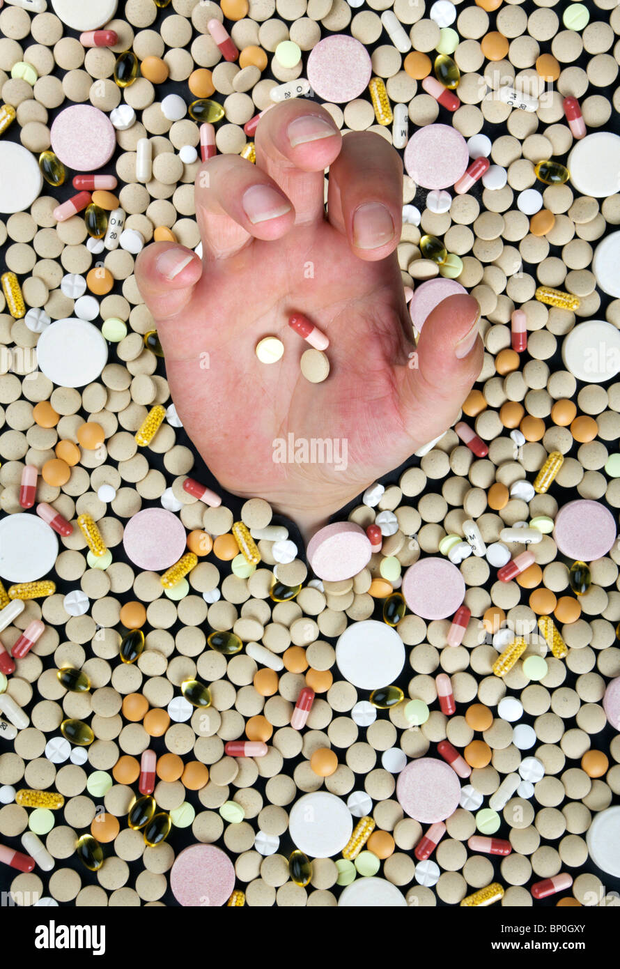 Affogare in un mare di medicina - mano protesa tra centinaia di pillole Foto Stock