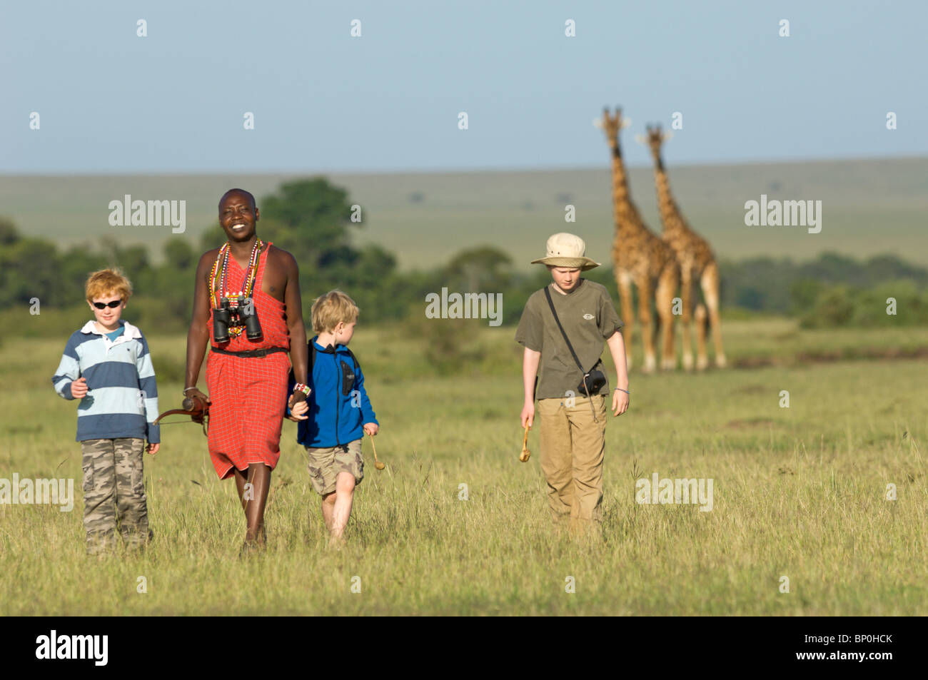 Kenia Masai Mara. Guida Safari, Salaash Morompi Ole, conduce i ragazzi su un gioco a piedi verso alcune giraffe Masai. (MR) Foto Stock