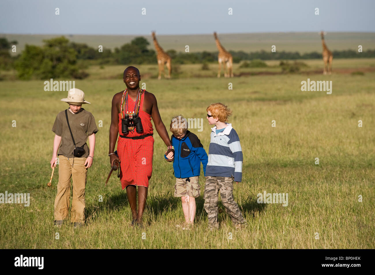 Kenia Masai Mara. Guida Safari, Salaash Morompi Ole, conduce i ragazzi su una boccola a piedi attraverso le pianure. (MR) Foto Stock