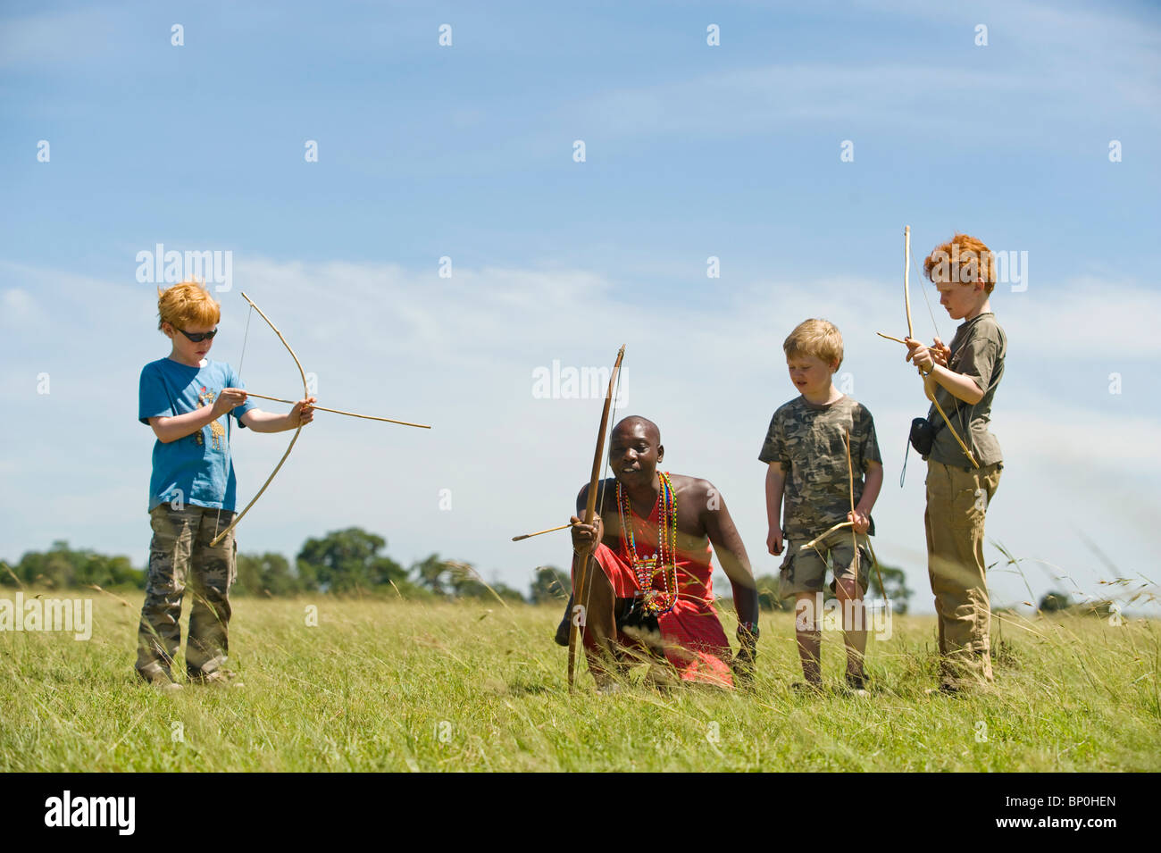 Kenia Masai Mara. Guida Safari, Salaash Morompi Ole, insegna ai bambini di tiro con l'arco stile Masai. (MR) Foto Stock