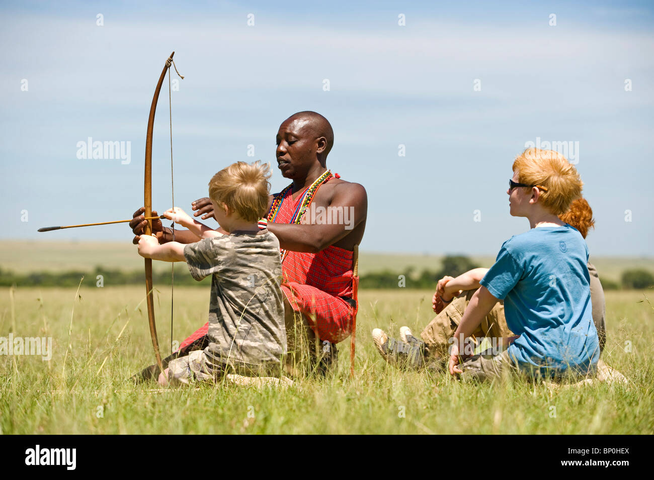 Kenia Masai Mara. Guida Safari, Salaash Morompi Ole, insegna ai bambini di tiro con l'arco stile Masai. (MR) Foto Stock