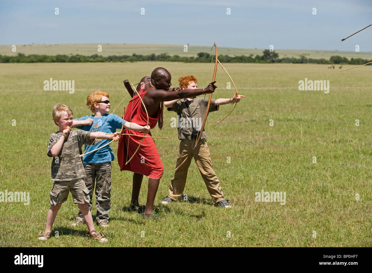 Kenia Masai Mara. Guida Safari, Salaash Morompi Ole, insegna ai bambini di tiro con l'arco stile Masai. (MR) Foto Stock