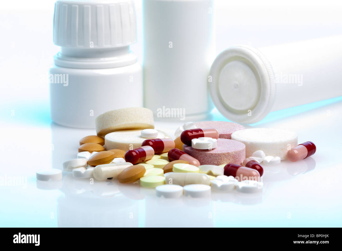 Cumulo di medicina pillole, compresse e capsule di fronte a loro bottiglie e contenitori Foto Stock