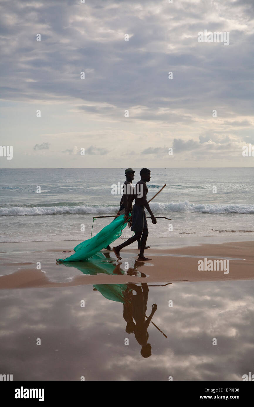 Mozambico, Tofo. Due pescatori a piedi con le loro reti da pesca lungo le spiagge di Tofo. Foto Stock