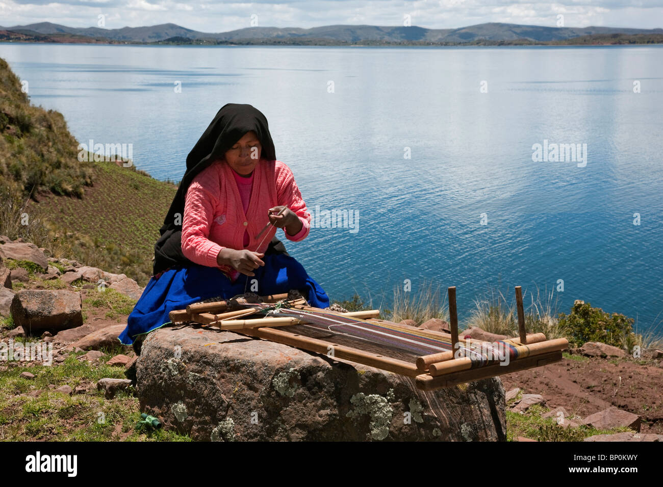 Il Perù, un Quechua-parlando la donna lavora la sua tradizionale telaio in legno sull'isola Taquile. Foto Stock