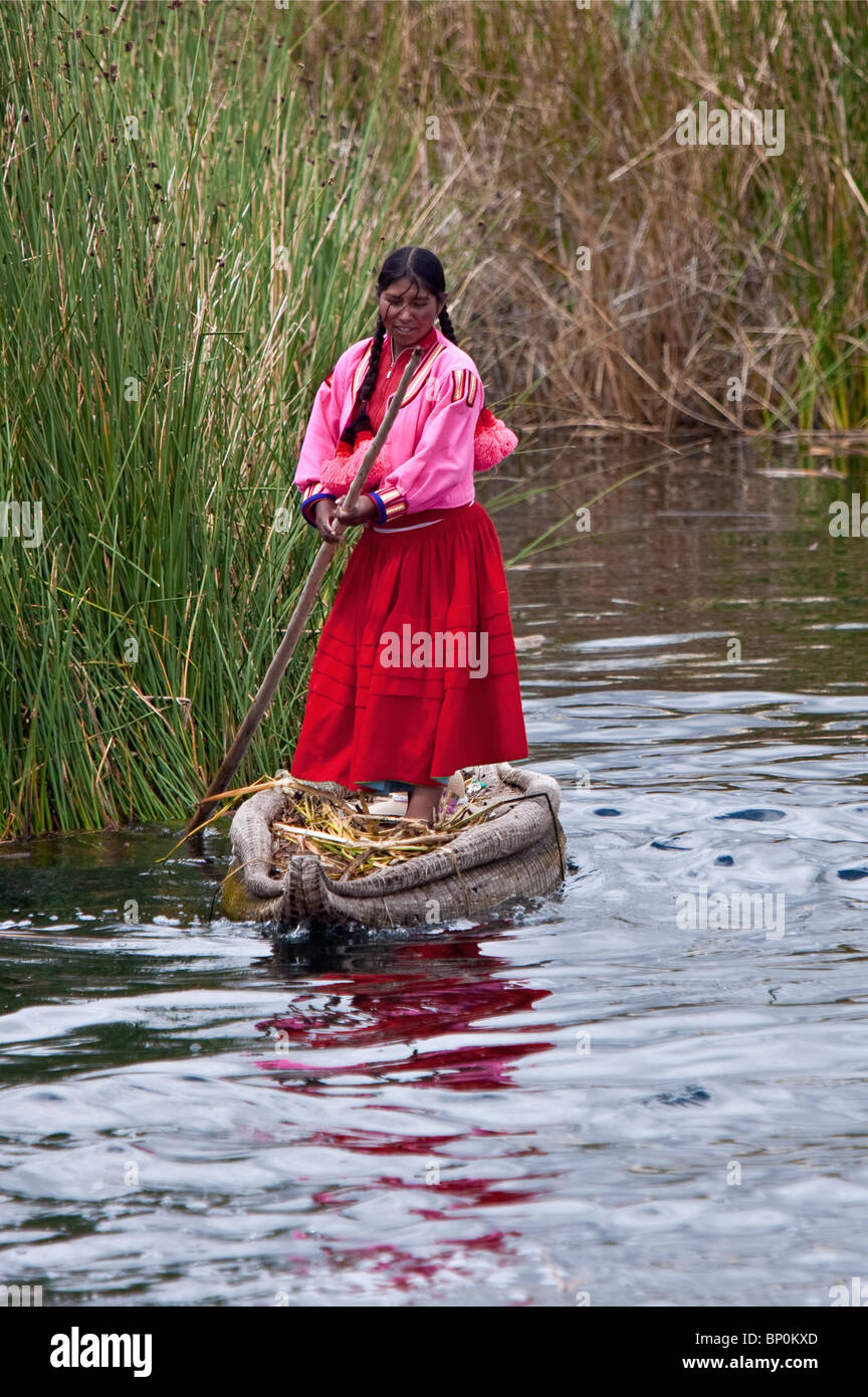 Il Perù, una ragazza di Uros poli il suo reed in canoa lungo un canale tra le uniche isole galleggianti del lago Titicaca. Foto Stock