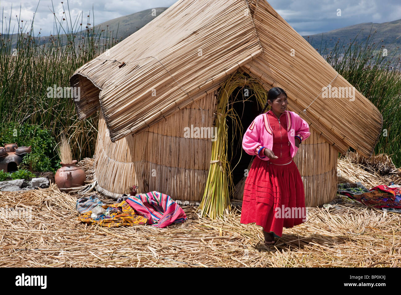 Il Perù, una ragazza di Uros fuori dalla sua casa a lamelle su una delle uniche isole galleggianti del lago Titicaca. Foto Stock