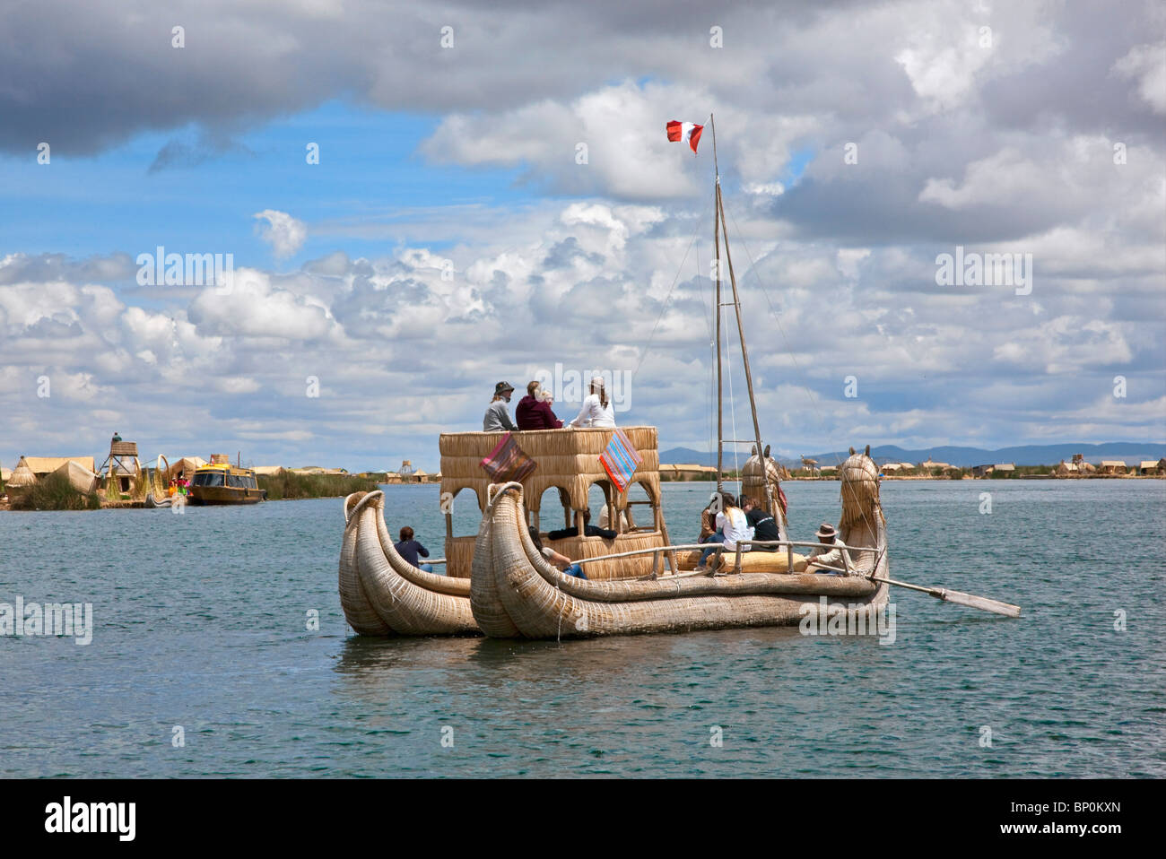 Il Perù, una grande barca reed è remato giù il canale principale tra le uniche isole galleggianti di Uros sul lago Titicaca. Foto Stock