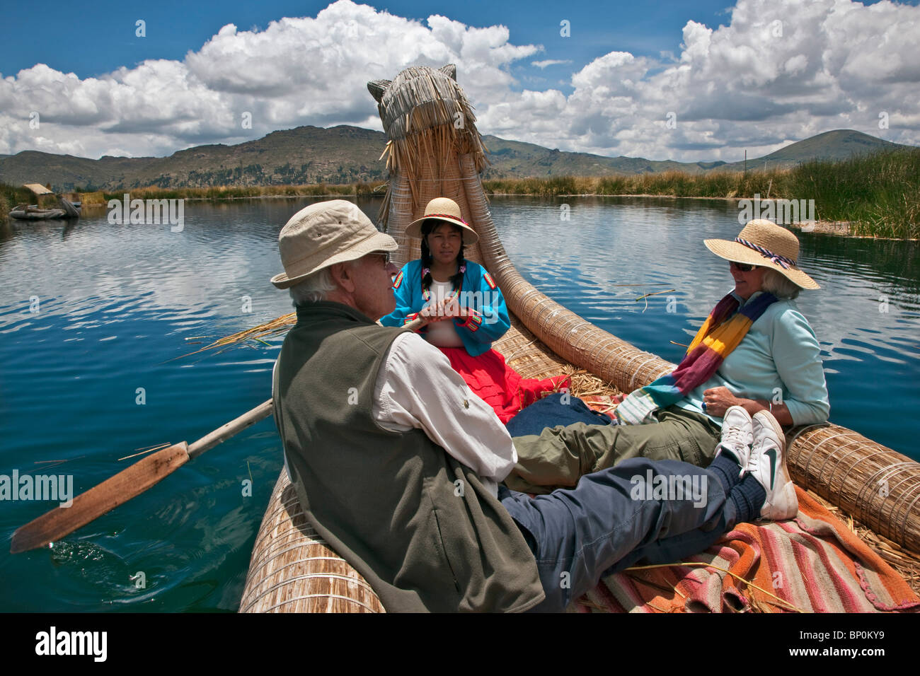 Il Perù, turisti essendo remando in una tradizionale barca reed intorno all'unica isole galleggianti di Uros sul lago Titicaca. Foto Stock