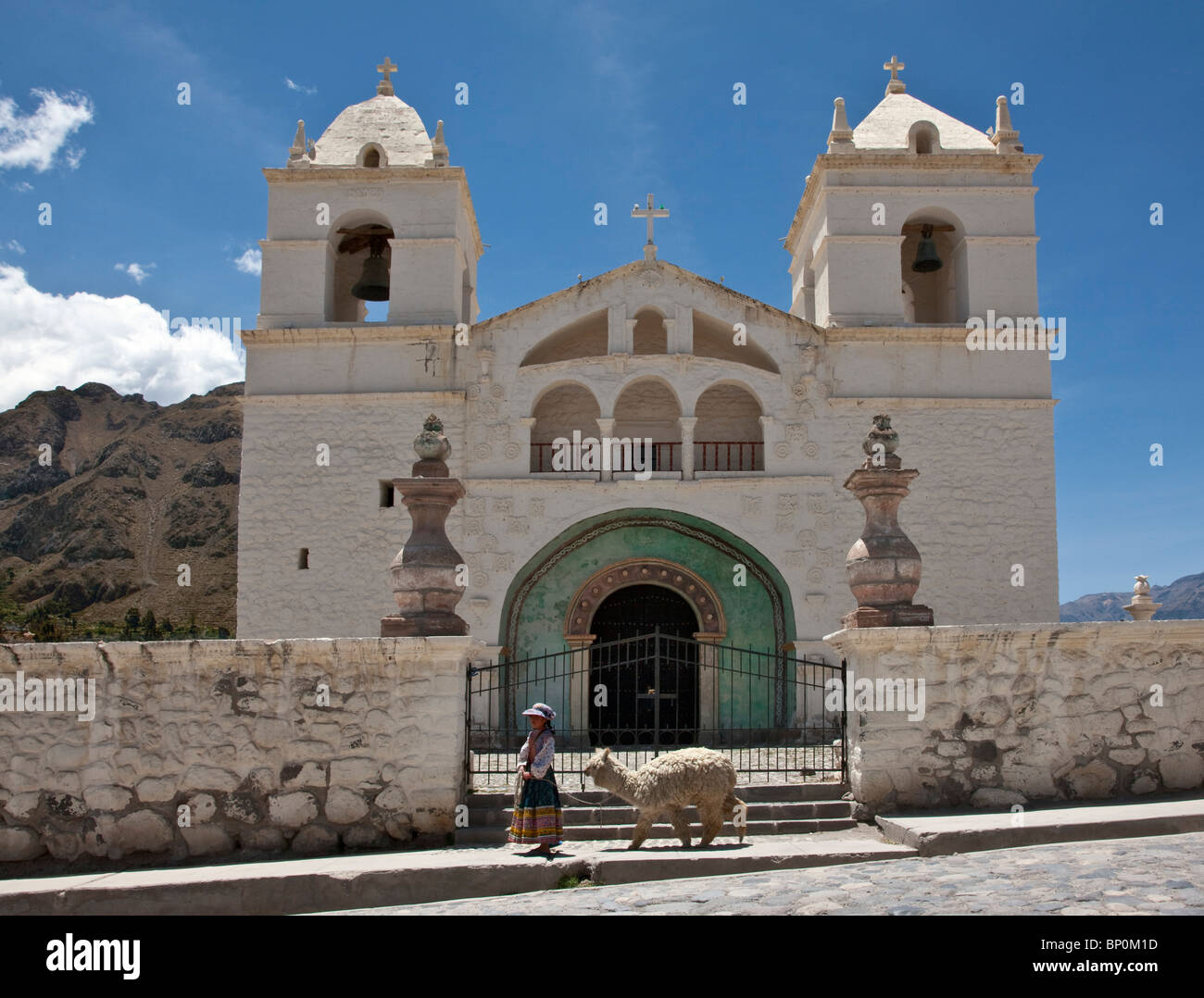 Il Perù, un Cabana girl conduce i suoi alpaca addomesticati passato chiesa di Maca, situato nella valle di Colca. Foto Stock