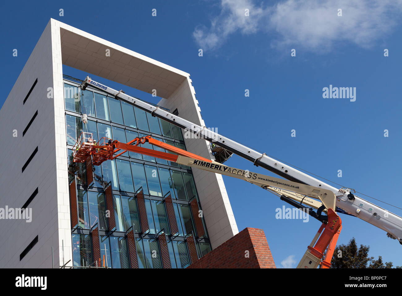 Lavoratori edili lavora in altezza per installare il rivestimento su Southern di funzionamento unità di comando Southampton Foto Stock